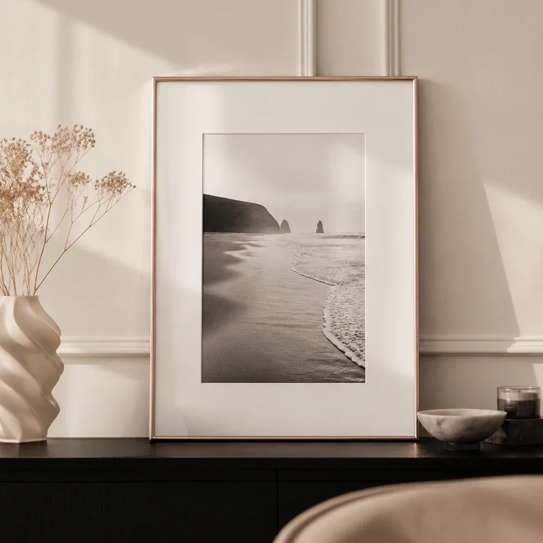 Witte kunststof lijst met zwart-witfoto van een strand en passe-partout op een ladekast