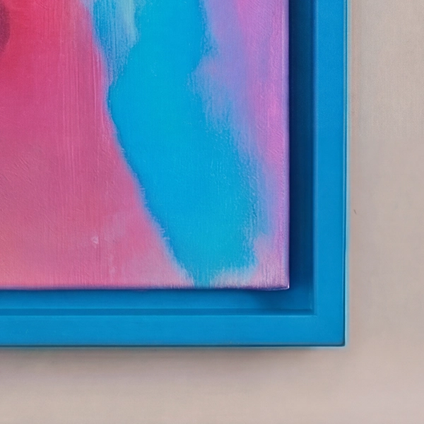 Close-up van een blauwe baklijst met een kleurrijk canvasdoek in roze en turquoise voor een lichtbeige muur.