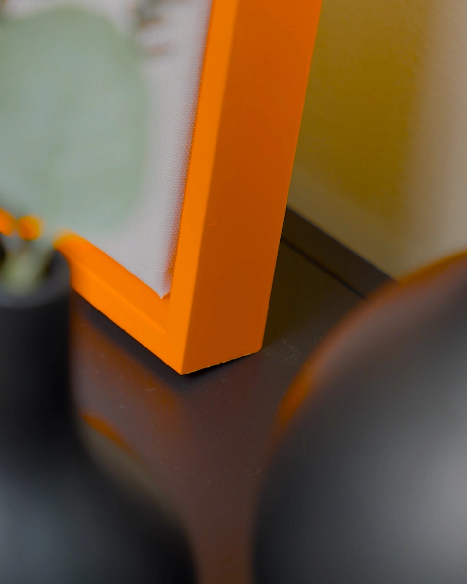 Detailopname van de hoek van de baklijst Jill in fel neonoranje voor canvasdoeken in een huiselijke sfeer
